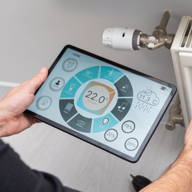 Ein Techniker checkt das Heizsystem in einer Wohnung mit einem Tablet